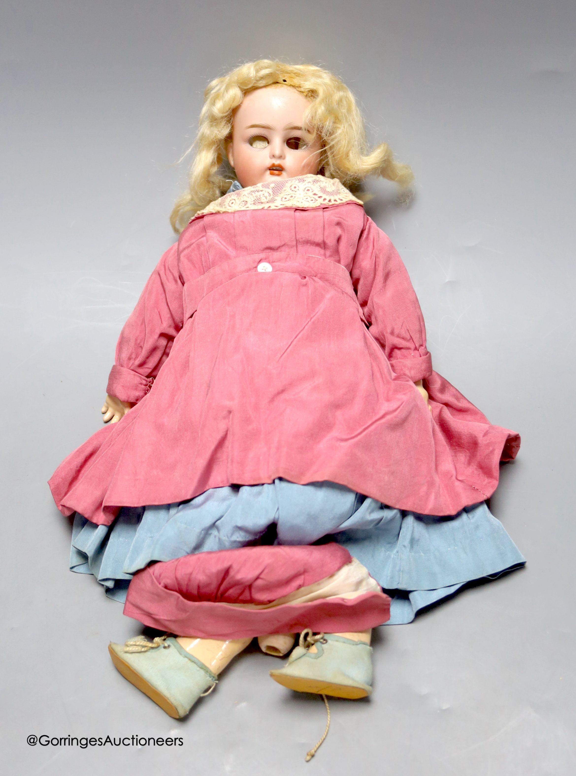 A Kammer and Reinhardt bisque porcelain doll, in original clothes and wig, lower part of left leg detached but present, eyes detached, 33cm tall.